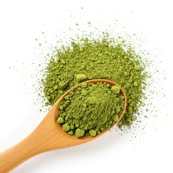 A wooden spoon filled with vibrant green matcha powder set against a scattered pile of the same powder on a white background photo
