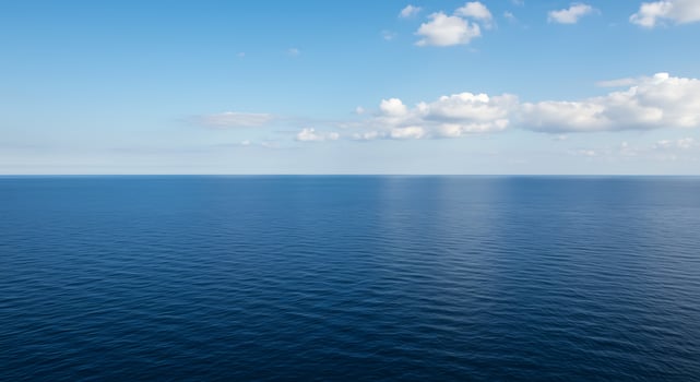 A large body of water with a few clouds photo