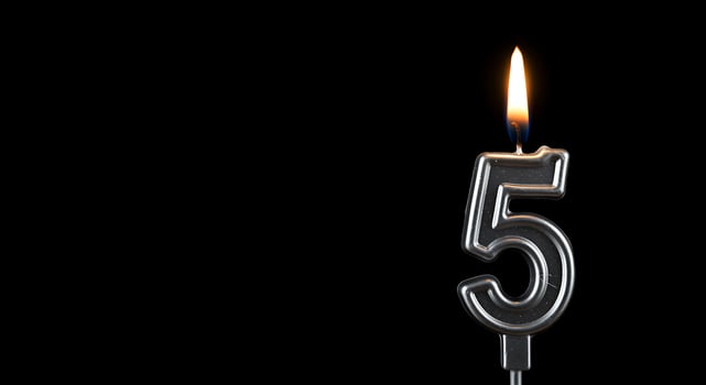 A candle is lit in the shape of the number five photo