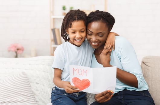 Family Love. Happy black mother hugging her adorable little daughter and reading greeting card, free space photo