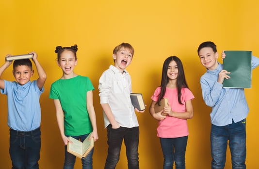 Children having fun with books, looking at camera on yellow background photo