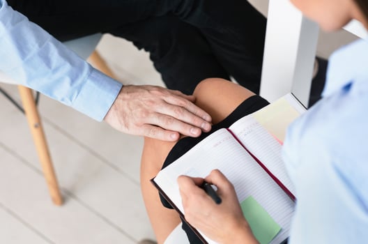 Sexual Harassment At Workplace. Unrecognizable Boss Harassing Young Female Colleague Touching Her Knee Working In Office. Cropped photo