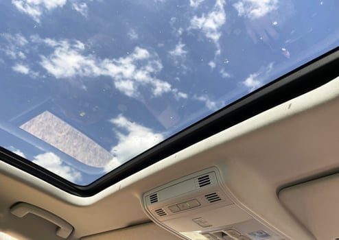 Car sunroof closed with blue sky visible through it photo