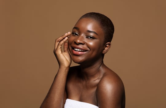 Essential Beauty. Portrait Of Attractive Black Lady With Clean Skin And Short Hair Smiling At Camera, Beautiful African American Female Wrappen In Towel Posing Over Brown Background, Copy Space photo