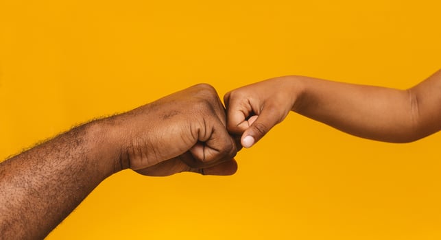 Family unity. African man and little girl fist bump, close up, orange panorama background photo