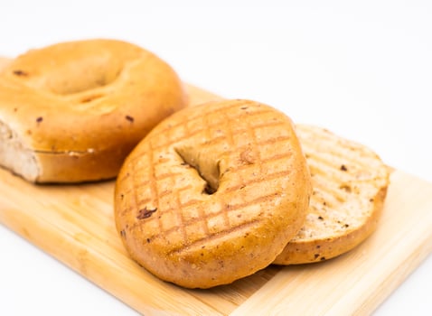 Toasted Whole Wheat Raisin Bagel on Wooden Board isolated on white background side view of Healthy Breakfast photo