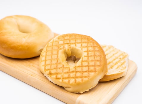 Plain Toasted Bagel on Wooden Board isolated on white background side view of Classic Breakfast photo