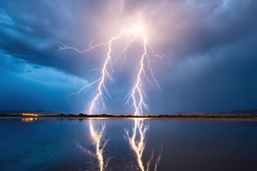Lightning bolts striking near a lake reflecting the cloudy sky during a dramatic thunderstorm photo