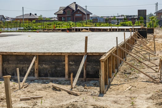 Workers are setting up a concrete foundation for a residential project in a growing suburban neighborhood under clear skies photo