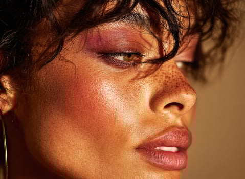 Model showing professional makeup and freckled skin posing for beauty campaign photo