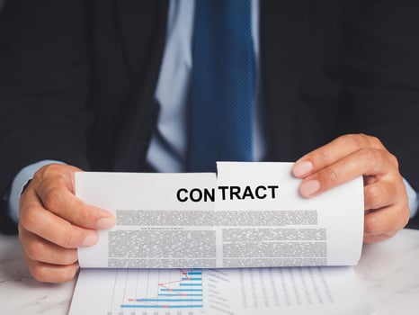 Close-up of a businessman in a suit tearing up a contract while sitting at the table photo