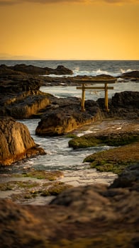 Serene Sunset at Coastal Japanese Shrine Torii Gate on Rocky Shore. photo