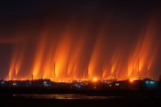 A large factory with smoke coming out of it at night photo