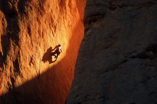 A climber is climbing up a rock face photo