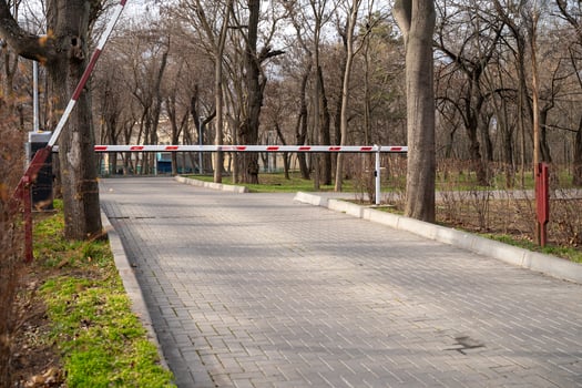 Automatic barrier, security system at the entrance to the city green park area. A path with trees on the side of a road photo