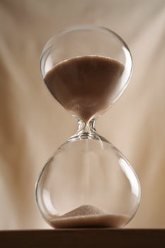 Minimalist Glass full time Hourglass on Wooden Surface with Beige Background hero shot low-key photo