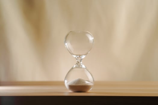 Minimalist Glass time over Hourglass on Wooden Surface with Beige Background photo
