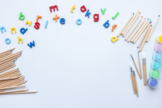 Colorful alphabet magnets and art supplies on white background photo