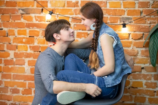 A guy and a girl in jeans clothes on a background of a brick wall photo