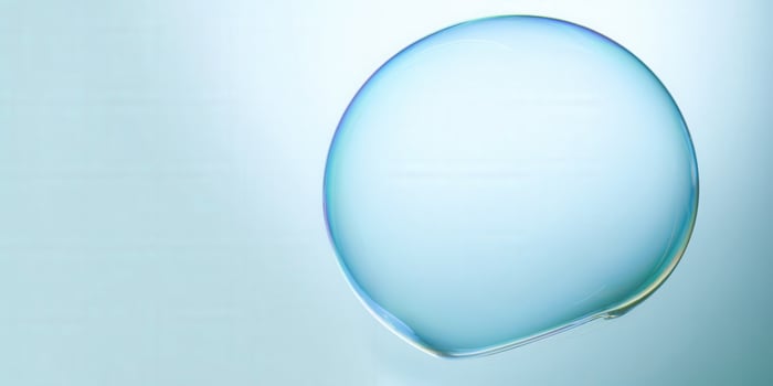 A large soap bubble floats with stunning iridescence against a soft blue backdrop. photo