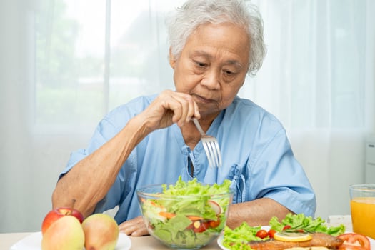 elderly woman patient eating salmon steak breakfast with vegetable healthy food in hospital. photo