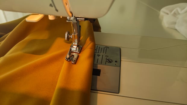 Sewing machine stitching yellow fabric, creating clothing photo