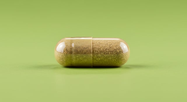 A pill on a green surface with a close up of the pill photo