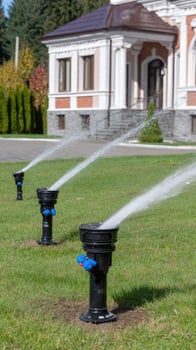 A sprinkler system is spraying water on a lawn photo
