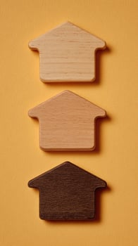 Three wooden house shaped magnets on a yellow background photo