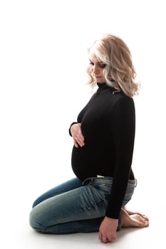 Young pregnant woman standing on pink background photo