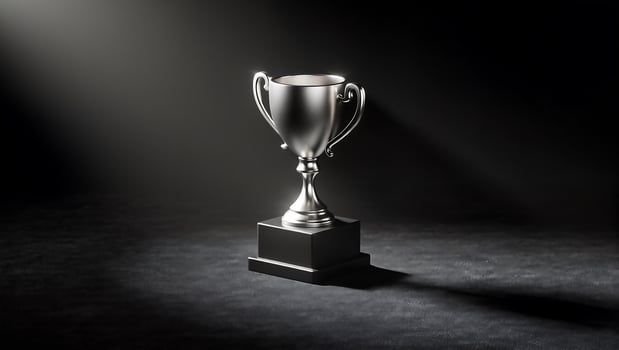 Trophy in Spotlight, A gleaming silver trophy, perched on a black base, stands majestically in a dramatic spotlight against a dark background. The image evokes feelings of success, achievement photo
