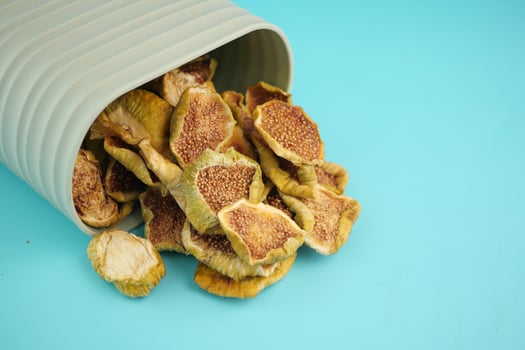 Dried figs spilling from a container on a blue background photo