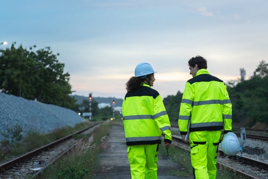 Railway Workers in High-Visibility Gear Walking on Tracks, Engineers or Technicians Inspecting Railroad at Dusk, Two Safety Personnel on a Train Track with Signal Lights photo