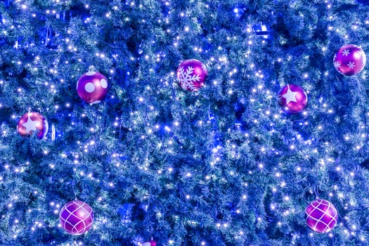 A blue christmas tree with many pink and purple balls photo