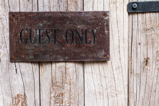 A sign on a wooden wall that says guest only photo