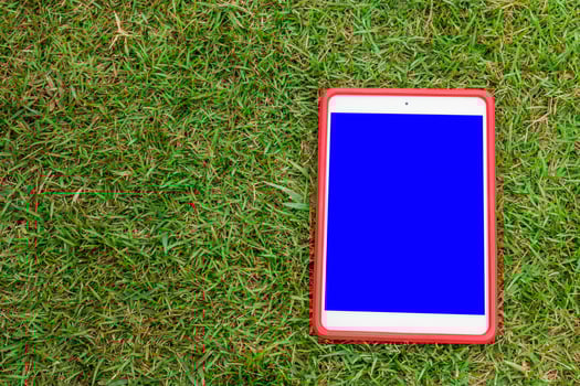 A red tablet with blue screen on the grass photo