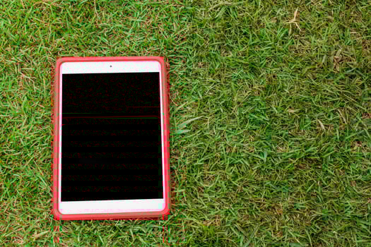 A red tablet computer is sitting on the grass photo