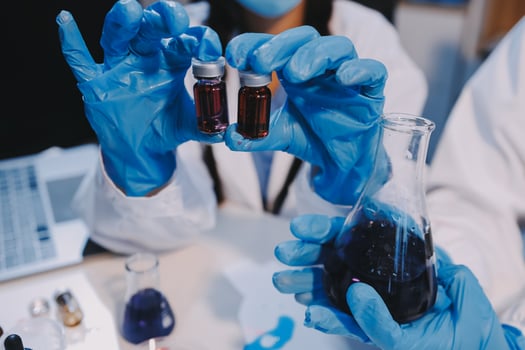 Two people in blue gloves holding test tubes photo