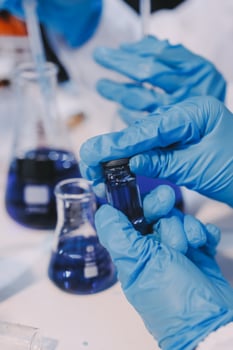 Hands in blue gloves holding blue liquid photo