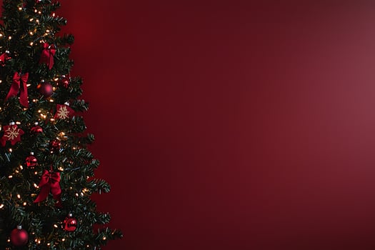 Festive Christmas Tree with Red Ornaments and Lights against a Deep Burgundy Background. Perfect for holiday greetings and winter celebrations. photo