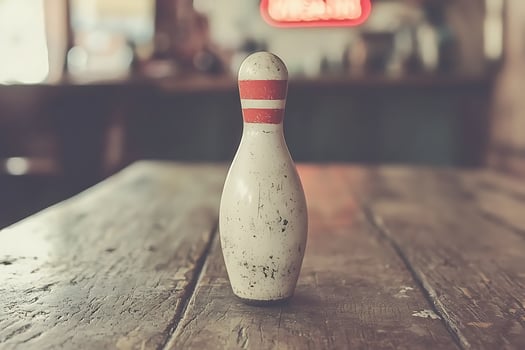 A Single, Weathered Bowling Pin on a Rustic Wooden Table. photo