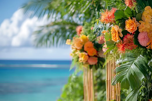 Vibrant Tropical Floral Arrangement with Ocean View. A stunning display of orange and pink flowers, lush greenery, and bamboo, set against a blurred turquoise ocean backdrop. photo
