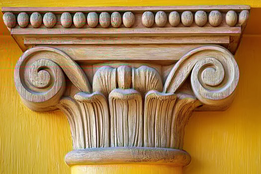 Intricate Carving of a Decorative Column Capital Against a Vibrant Yellow Wall. photo