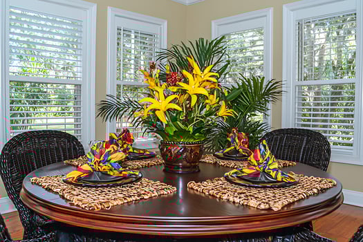 Sunlit Dining Room with Tropical Flower Arrangement and Place Settings. photo