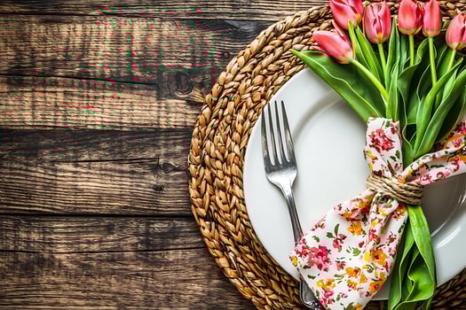 Elegant Spring Table Setting with Tulips and Place Setting. A rustic wooden background enhances the beauty of the floral arrangement. photo