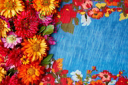 Vibrant Autumn Flowers on a Colorful Floral Fabric Background. A border of red, orange, and pink blossoms creates a beautiful frame for your design. photo