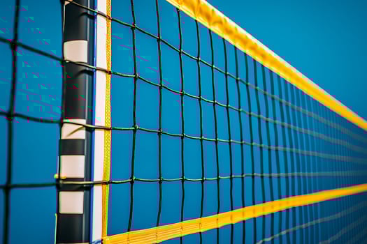 Close-up of a Volleyball Net Against a Vibrant Blue Sky. The image showcases the intricate details and bright colors of the sports equipment. photo
