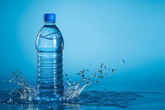 Refreshing Hydration Plastic Bottle of Water Splashing into Blue Liquid. photo