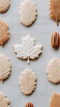 Autumn leaf-shaped cookies with white icing and pecans on neutral linen background. Fall baking seasonal homemade treats with copy space for text in cozy rustic style. photo