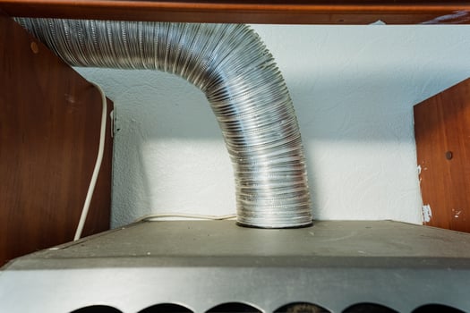 The kitchen is equipped with a highly functional hood that features a sturdy metal hose, which is securely attached to ensure effective ventilation and optimal air circulation while cooking photo
